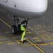 A ground crew worker connects a fuel hose to a jet