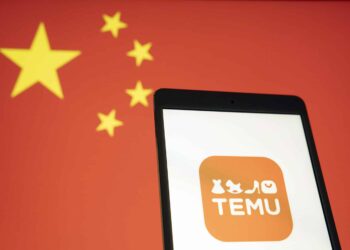 Temu logo on a cell phone against a backdrop of China's flag
